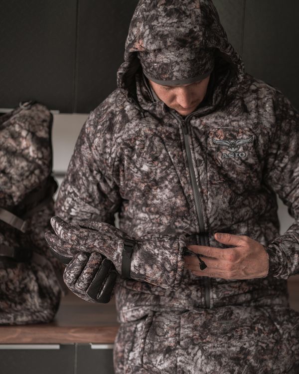 Hunter adjusting ASIO Gear RAPTOR camo heavyweight gloves with full late-season system before field use