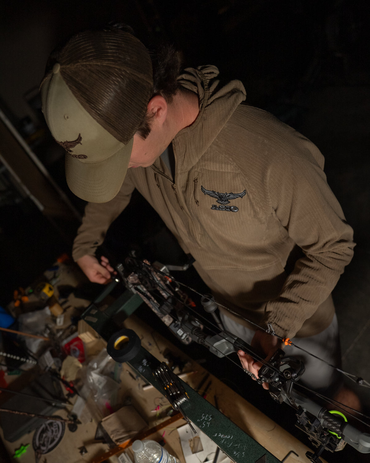 ASIO Gear hunter tuning his bow wearing midweight hoodie field brown