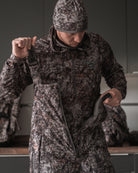 Hunter wearing ASIO Gear Heavyweight Bib in RAPTOR camo, showing front zip and branded suspenders