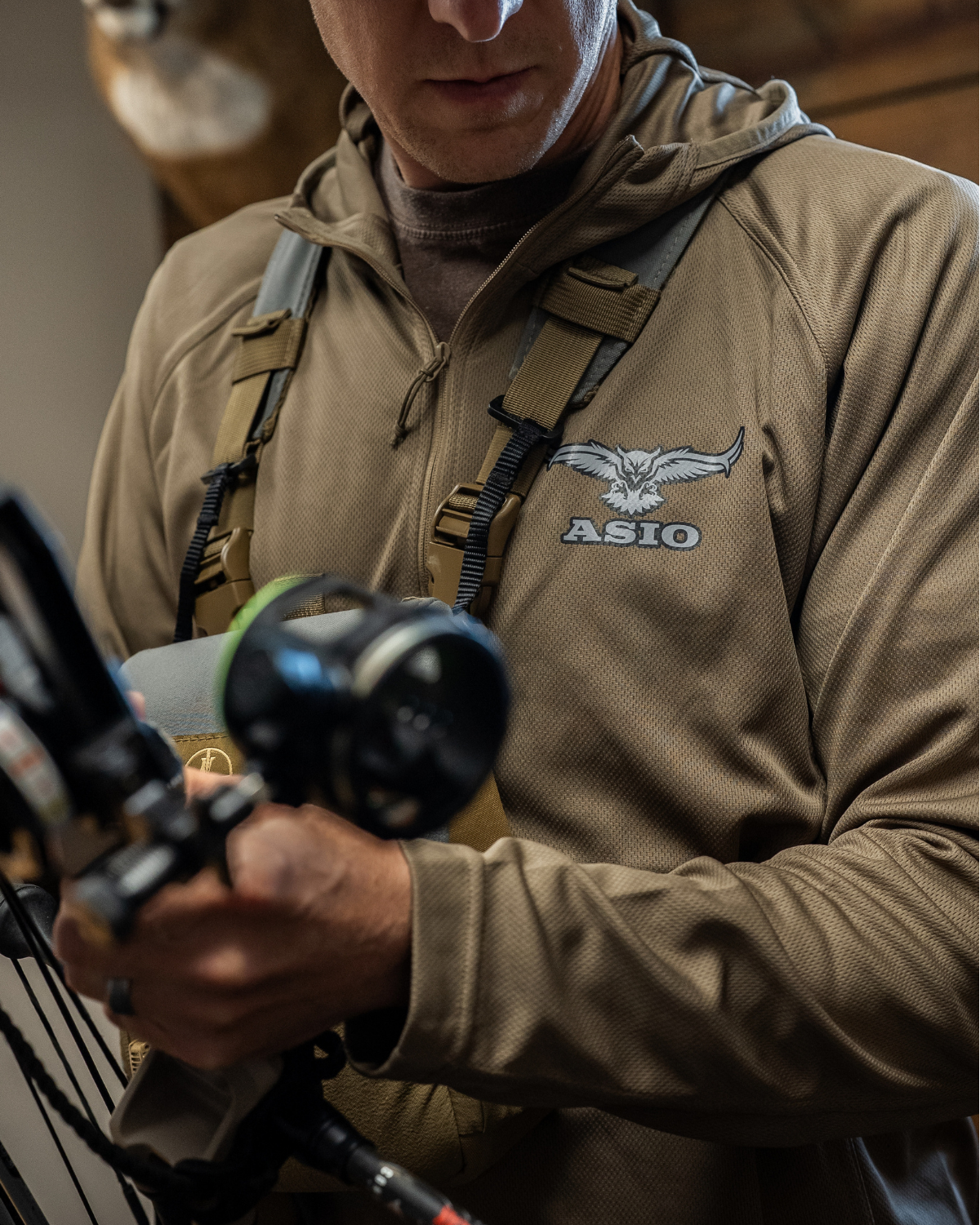 Bowhunter at full draw wearing the ASIO Lightweight Hoodie in Field Brown
