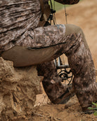 Close-up of ASIO Gear Midweight Bomb Pant in RAPX camo highlighting reinforced seat and knee panels for whitetail bowhunting